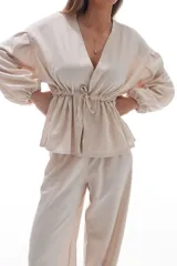 Blusa color crema con escote en V, mangas largas abullonadas y cintura ajustable con cordón.