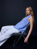 Camisa sin mangas de lino a rayas verticales celestes y blancas, con cuello con solapa, escote en V, abertura central con botones y bolsillo en el pecho.