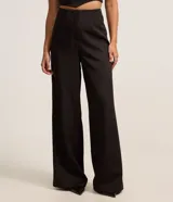 Pantalón de vestir negro de corte recto, sin cintura, con pinzas delanteras y cierre con cremallera y gancho.