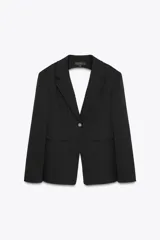 Blazer negro de cuello solapa y manga larga con hombreras. Tiene bolsillos de vivo en delantero y pecho, detalle de aberturas en espalda, botón y forro interior a tono.