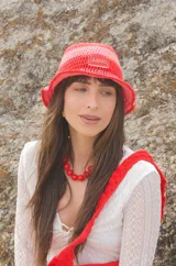 Sombrero tipo bucket tejido a crochet a mano, con hilo 100% algodón y diseño a rayas en tonos rosa y rojo. Presenta una etiqueta con el logo de la marca Cilento en el frente.