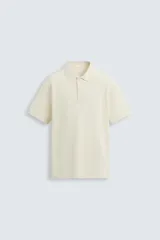 Polo color crema con textura de rayas horizontales, corte regular fit, cuello solapa y cierre frontal con botones.