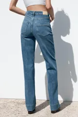 Pantalón de jean de tiro alto con bolsillos frontales y traseros. Corte recto y cierre frontal con cremallera y botón.