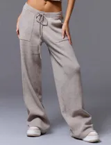 Conjunto de chaleco corto de punto con botones y pantalón de punto con bolsillos grandes y lazo en la cintura, color beige.