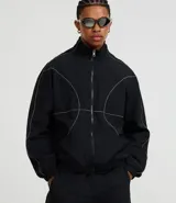 Campera deportiva negra con cuello alto, cierre frontal de cremallera y elásticos en puños y bajo. Presenta recortes geométricos definidos por costuras en hilo reflectante.