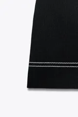 Minifalda negra de tiro alto con cintura elástica y costuras blancas a contraste.