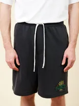 Bermuda de felpa negra con cintura elástica ajustable con cordón blanco. Presenta un estampado con un sol y el logo de la marca en la pierna derecha.