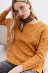 Sweater color mostaza de tejido de punto con detalle de lentejuelas integradas al hilado, calce holgado y mangas largas.