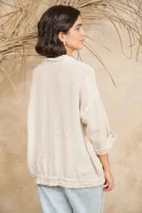 Camisa blanca de lino con cuello mao, mangas 3/4 con botón para sujetar, cierre con botones a tono y ajuste con cordón en la cintura.