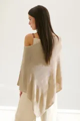 Poncho color beige de tejido de punto con cuello asimétrico.