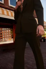 Pantalón marrón de vestir, de tiro medio y corte recto. Presenta bolsillos delanteros, cierre frontal con cremallera y gancho metálico.