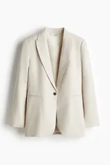 Blazer color beige de lino y viscosa, con solapas de pico, hombreras finas, cierre de un botón, pinzas en la cintura, abertura con botón en los puños, bolsillos delanteros ribeteados y abertura atrás.