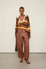 Top de punto de manga larga con cuello polo blanco, escote en V profundo y rayas horizontales en tonos marrón y mostaza. Los puños y el bajo son acanalados.