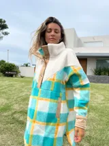 Buzo largo con cuello alto de polar color crema y cuerpo con estampado de cuadros en tonos celeste, amarillo y blanco.
