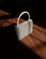 Cartera de mano rígida color negro, cubierta de strass plateado brillante. Tiene asa corta superior y cierre de broche.
