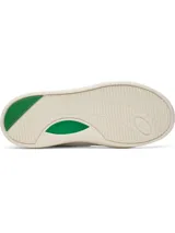 Zapatillas deportivas de mujer Under Armour modelo UA W Flex, color blanco con detalles en verde esmeralda. Presentan una silueta de corte bajo inspirada en el estilo retro de baloncesto, con parte superior de cuero y suela de goma color crema. El logo de Under Armour es visible en el lateral y en el talón.