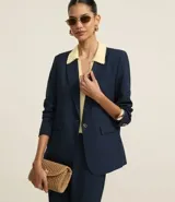 Blazer azul marino de corte sastrero, con solapas con detalle de puntilla en color crema, cierre con un botón dorado y bolsillos delanteros con solapa.