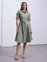 Vestido camisero blanco de algodón con cuello con solapa, delantera abotonada, mangas 3/4 regulables con presilla y botón, y cintura con lazo de ajuste.