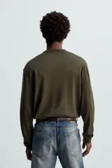 Jersey verde oscuro de punto fino, con cuello en V y mangas largas.