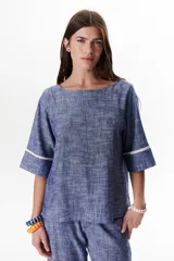 Blusa azul de lino con escote barco y mangas 3/4 con detalle de ribete blanco.
