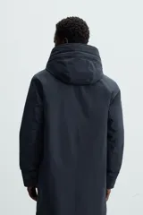 Parka azul marino de corte recto, con capucha y cuello alto desmontable. Interior acolchado, cierre frontal con cremallera oculta y botones a presión, bolsillos laterales y puños de rib.
