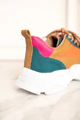 Zapatillas deportivas con paneles de cuero, gamuza y malla en colores naranja, marrón, verde, lila y crema. Cordones gruesos multicolor y suela chunky blanca.