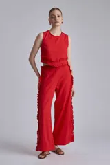 Conjunto de dos piezas color rojo vibrante, compuesto por un top sin mangas con detalle de volado fruncido en el bajo y un pantalón ancho de tiro alto con volados largos a lo largo de las costuras laterales.