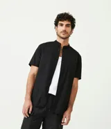 Camisa negra de algodón con corte slim, cuello mao, manga corta y abotonadura frontal.