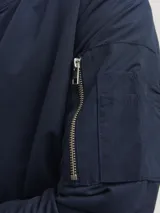Campera bomber azul marino de corte clásico, con cuello y puños acanalados, cierre frontal con cremallera, bolsillos laterales con cremallera y bolsillo en la manga.