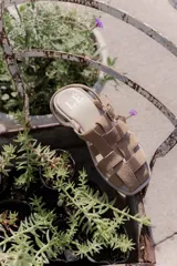 Sandalias de cuero marrón con diseño de tiras entretejidas y hebilla lateral.