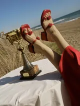 Sandalias rojas de tiras finas con detalle de rosetas en el empeine y tacón cuadrado.