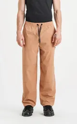 Pantalón beige de corte ancho, con cintura y puños elásticos, bolsillos laterales y logo estampado en la pierna.