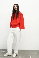 Sweater de punto color naranja con cuello redondo y mangas anchas hasta el codo.