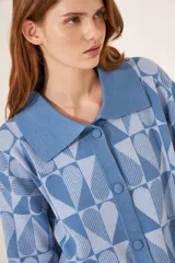 Cardigan azul con estampado de corazones geométricos en dos tonos de azul, con cuello polo y cierre frontal con botones.