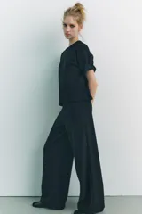 Pantalón negro de pierna ancha confeccionado en tejido de punto canalé con algodón. Tiene tiro medio y cintura con elástico interior.