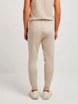 Pantalón de jogging verde oscuro, corte babucha, con cintura ajustable con cordón y bolsillos laterales.