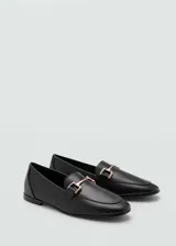Mocasines negros de cuero con punta almendrada y detalle de hebilla dorada.