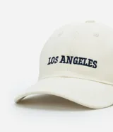Gorra de sarga color crema con visera curva y bordado frontal con la frase "Los Angeles" en azul marino.