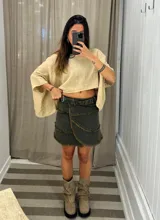 Minifalda tipo portafolio de denim color verde oscuro/gris, con borde deshilachado y ajuste lateral con tira y ojalillos metálicos.