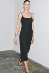 Vestido midi negro de breteles finos regulables, escote recto y abertura en el ruedo.