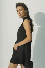 Top sin mangas color negro, con cuello alto y textura arrugada o plisada. Corte holgado con bajo asimétrico.