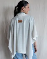 Ruana tejida con lana suave, color gris claro, con textura en relieve.