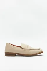 Mocasines color beige de símil cuero, con punta cuadrada, detalle de bordado a tono en la capellada y taco de 2,5cm.