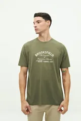 Remera verde militar de manga corta con estampa frontal con el texto "Brookfield The Emporium of Postmodern Activity No 1001 Torino | 1971".