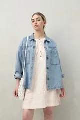 Vestido corto blanco de algodón con bordado floral en relieve, escote redondo con abotonadura frontal y mangas amplias.