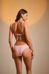 Traje de baño de dos piezas color rosa claro, tejido con textura. El corpiño es de corte triangular con tirantes finos que se atan en los hombros. La bombacha es de corte clásico.