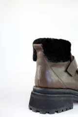 Bota corta de cuero color marrón con puntera y empeine de gamuza color beige. Tiene cuello de piel sintética color crema, cierre con velcro y suela track.