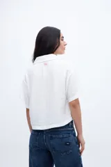 Blusa verde con escote en V, cuello camisero, manga corta y dos bolsillos en el pecho.