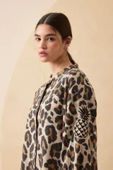 Vestido camisero largo de lino con estampado animal print, cuello mao y cierre frontal con botones. Tiene bordado de piña en la manga.