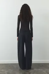 Pantalón negro de tiro alto, corte ancho y largo midi. Incluye bolsillos delanteros, pinzas y cinturón de la misma tela.